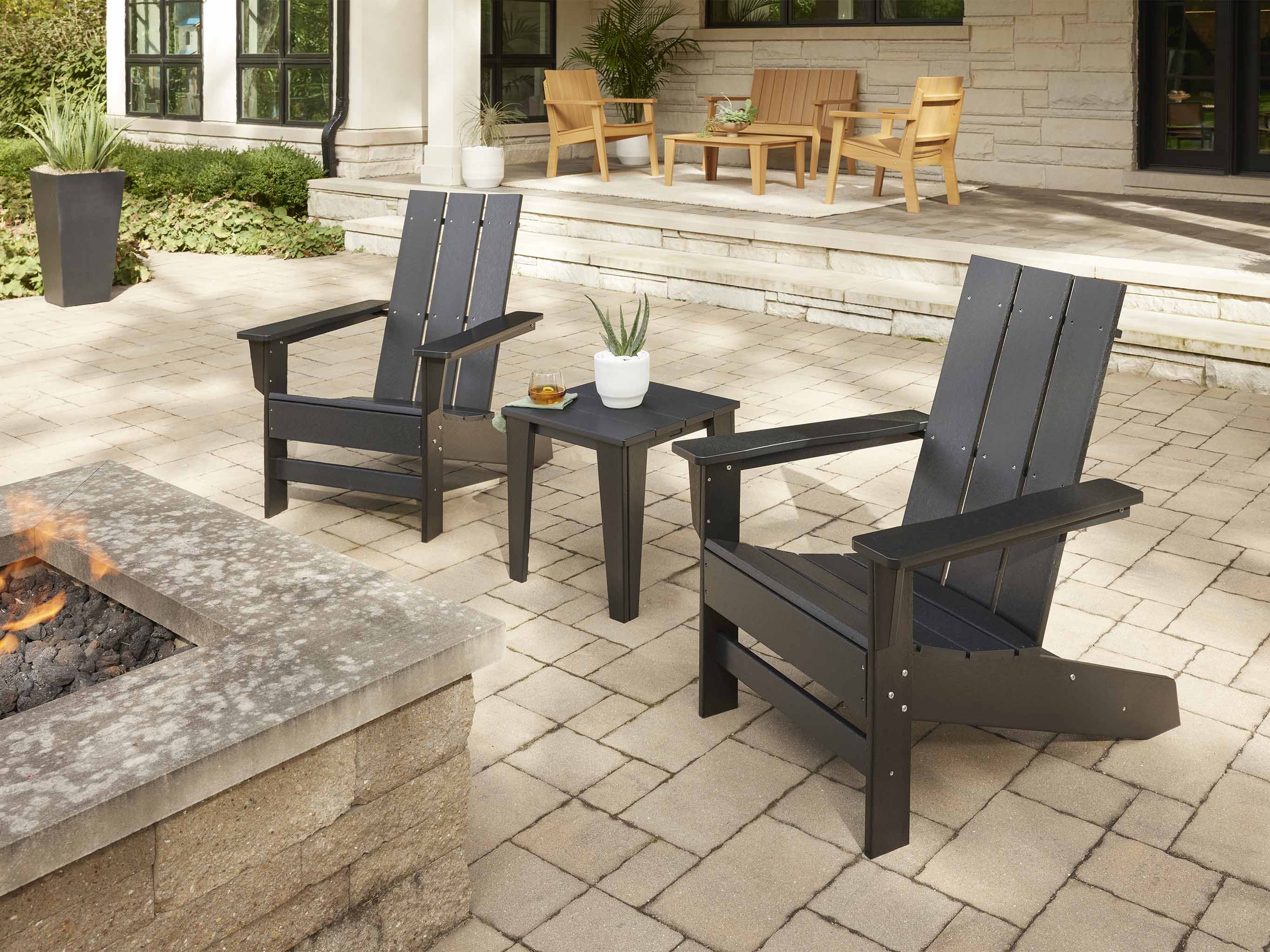 Black Two Aria Adirondack Chairs by stone firepit and modern side table
