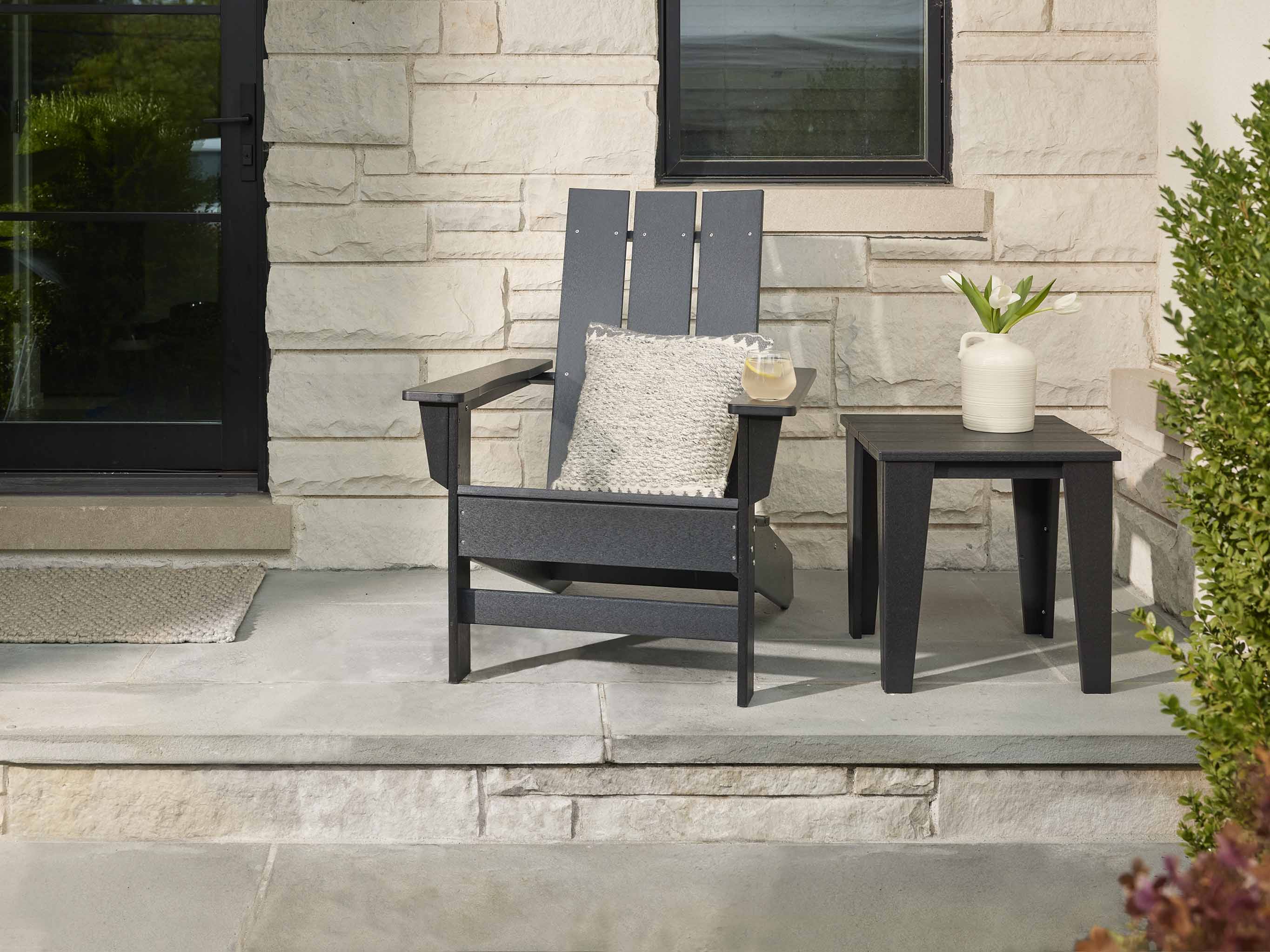 Black Aria Adirondack Chair on front porch with modern side table and pillow