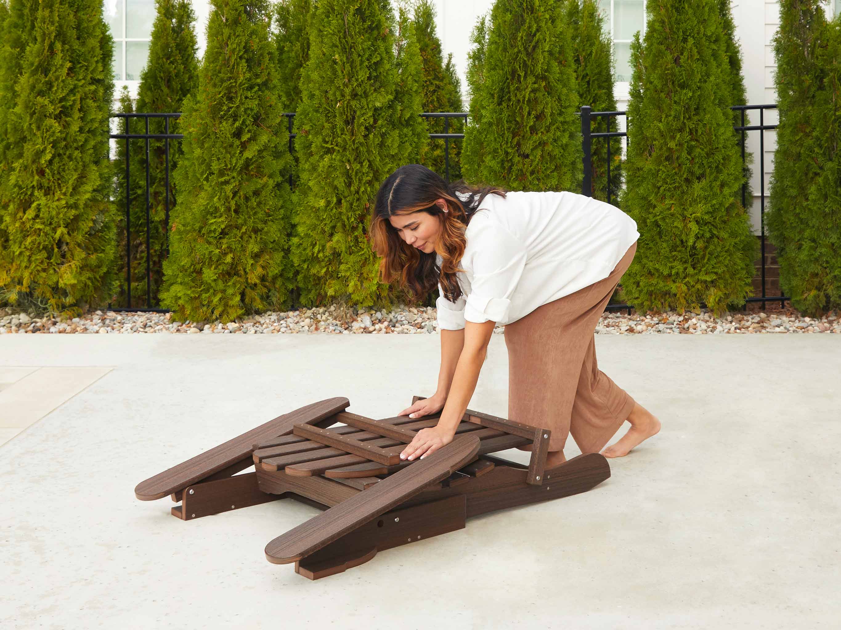 Brazilian Walnut Folding Adirondack Chair being folded by woman